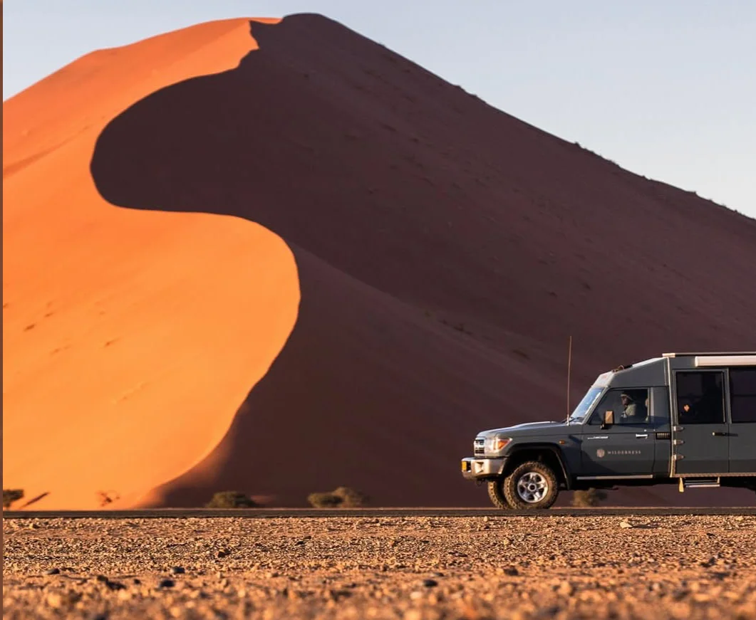Safari vehicle on desert road at the base of red sand dunes of sossusvlei